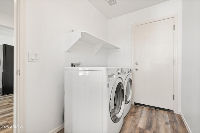 washroom featuring visible vents, washer and dryer, wood finished floors, baseboards, and laundry area