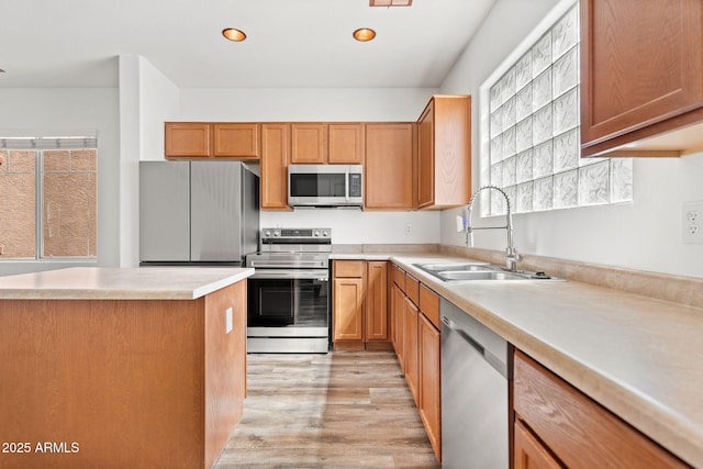 kitchen featuring light wood finished floors, light countertops, recessed lighting, appliances with stainless steel finishes, and a sink