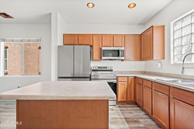 kitchen featuring visible vents, a sink, a center island, light wood-style floors, and appliances with stainless steel finishes