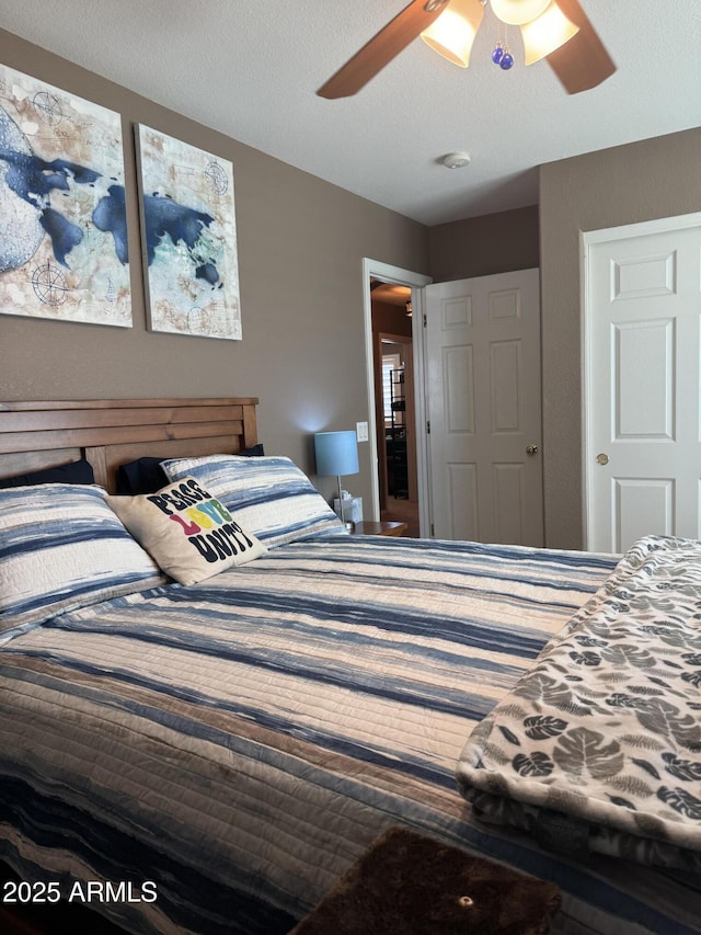 bedroom with a ceiling fan and a textured ceiling