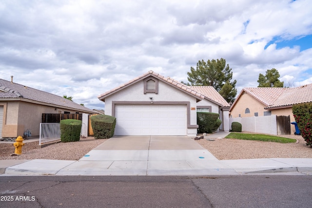 view of front of home featuring stucco siding, fence, concrete driveway, a garage, and a tiled roof