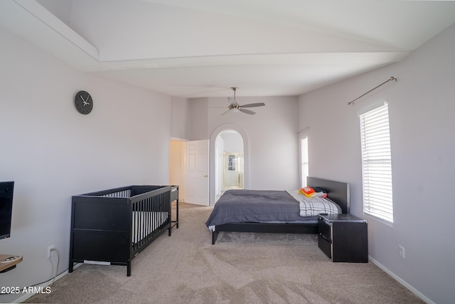 bedroom with baseboards, carpet, vaulted ceiling, arched walkways, and a ceiling fan