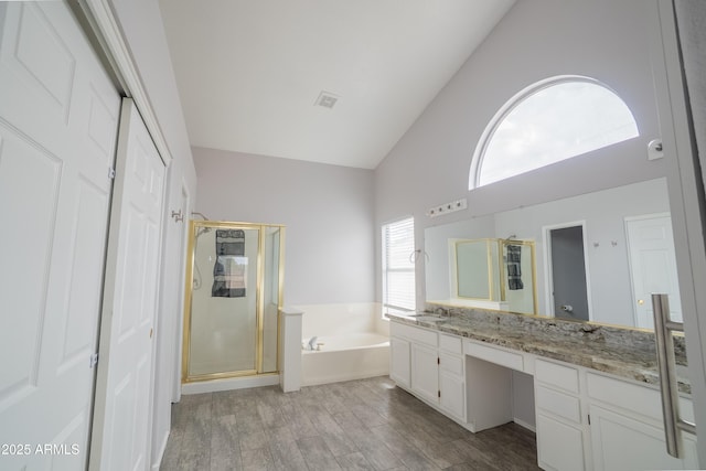 bathroom with a garden tub, vanity, a shower stall, and vaulted ceiling