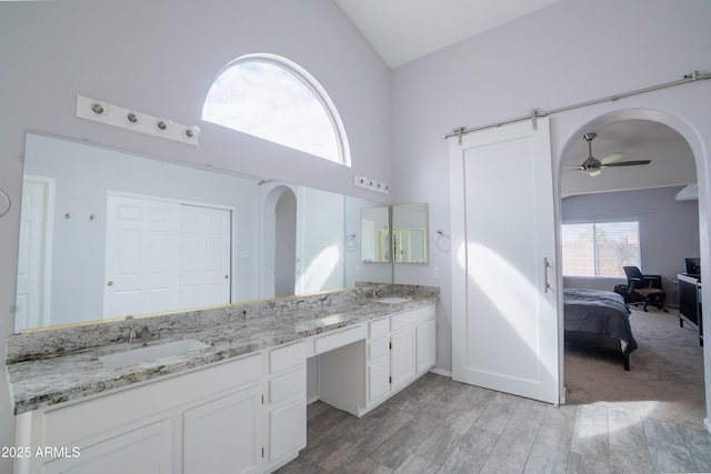 bathroom with double vanity, high vaulted ceiling, ceiling fan, and a sink