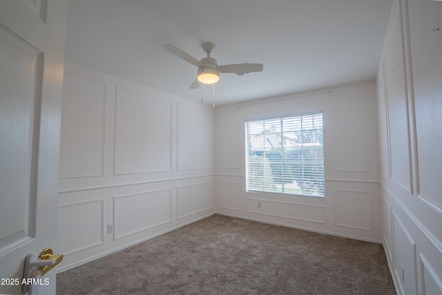 empty room featuring a decorative wall, carpet flooring, and ceiling fan