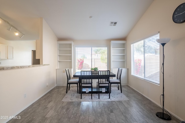 dining area featuring visible vents, plenty of natural light, wood finished floors, and vaulted ceiling