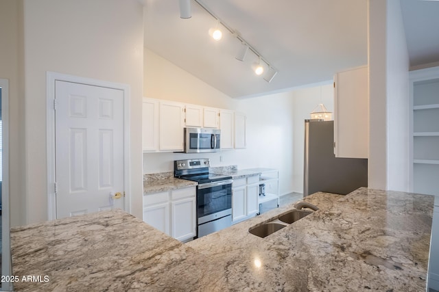 kitchen with a sink, stainless steel appliances, light stone countertops, and white cabinetry