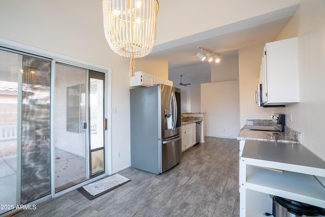 kitchen featuring stainless steel appliances, light countertops, white cabinetry, ceiling fan with notable chandelier, and light wood-type flooring