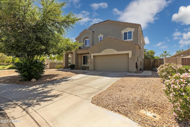 view of front of property with concrete driveway, an attached garage, fence, and stucco siding