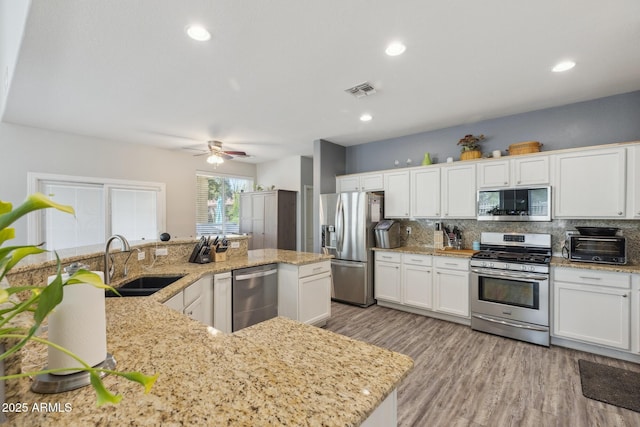 kitchen featuring a sink, appliances with stainless steel finishes, white cabinets, and backsplash