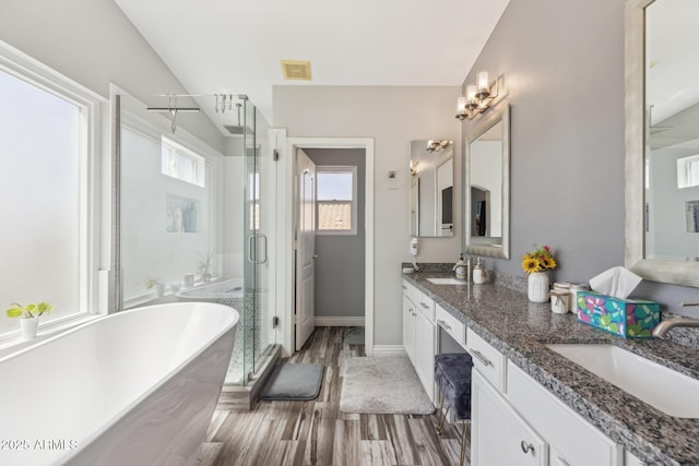 bathroom with visible vents, a sink, a soaking tub, and a shower stall
