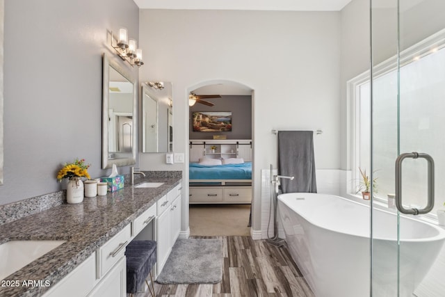 ensuite bathroom with connected bathroom, ceiling fan, a sink, double vanity, and wood finished floors