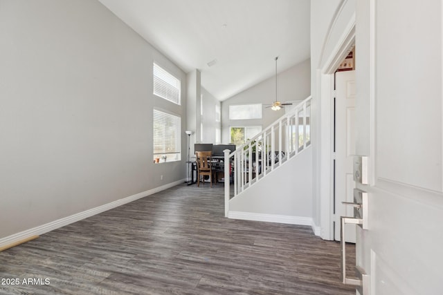 foyer entrance featuring baseboards, wood finished floors, stairway, and high vaulted ceiling