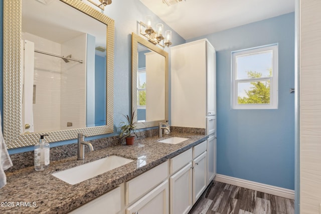 bathroom featuring a sink, baseboards, double vanity, and wood finished floors