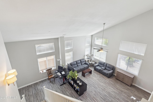 living area with baseboards, ceiling fan, and lofted ceiling