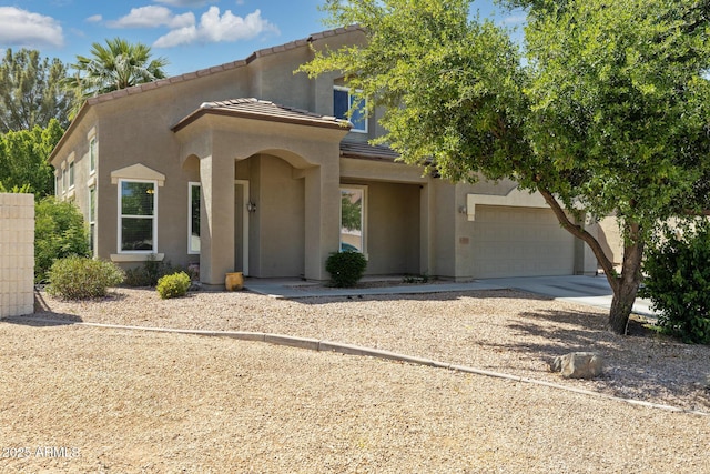mediterranean / spanish home featuring concrete driveway, a garage, a tile roof, and stucco siding