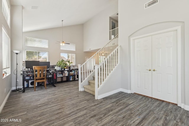 foyer entrance with ceiling fan, visible vents, wood finished floors, stairway, and high vaulted ceiling