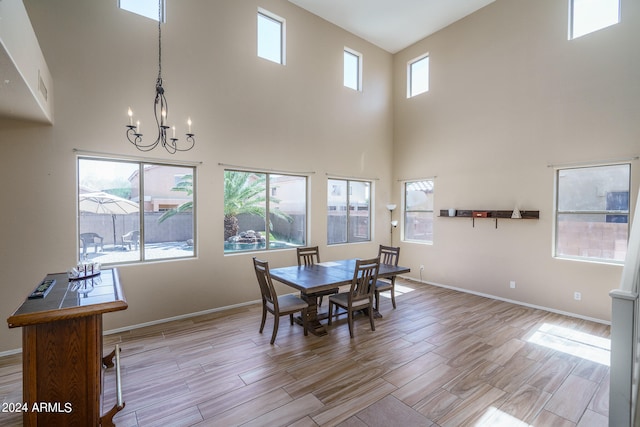 dining room with light hardwood / wood-style flooring, a high ceiling, an inviting chandelier, and a healthy amount of sunlight