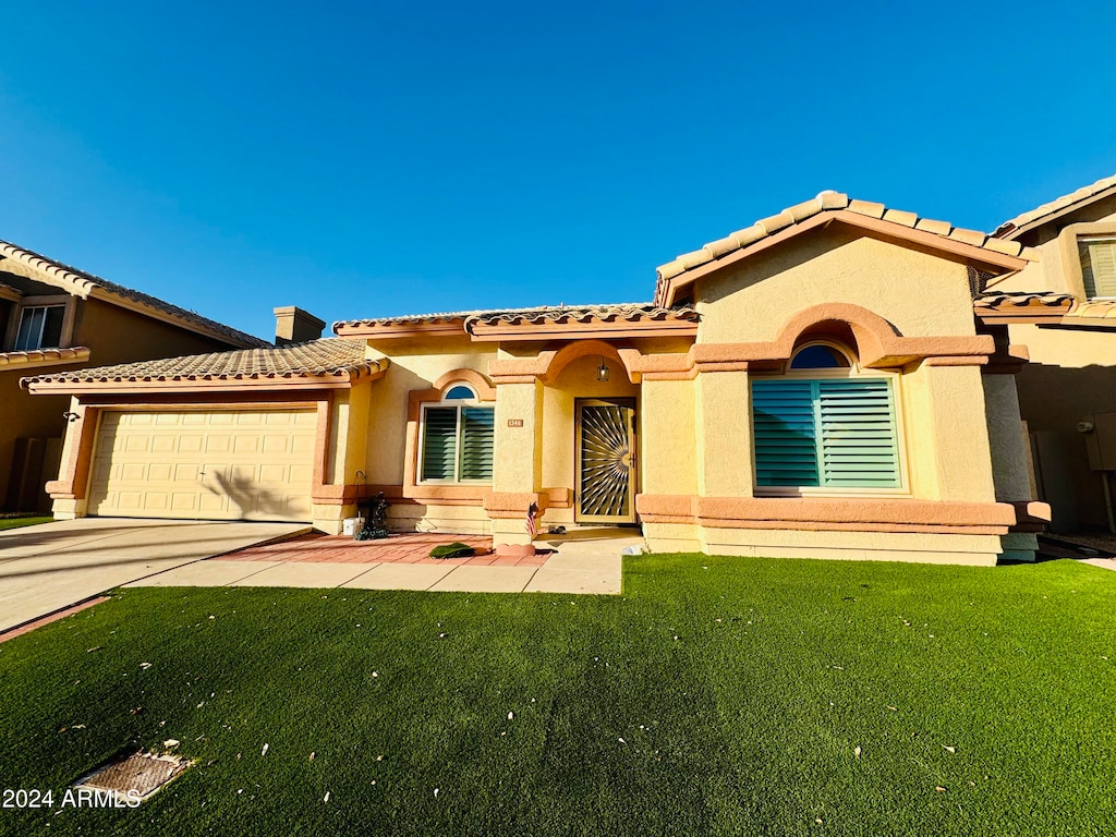 mediterranean / spanish home with a garage and a front lawn