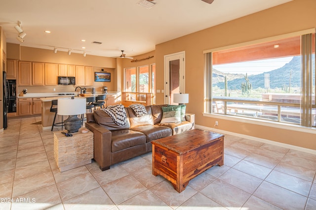 living room with rail lighting, light tile patterned floors, a mountain view, and a healthy amount of sunlight