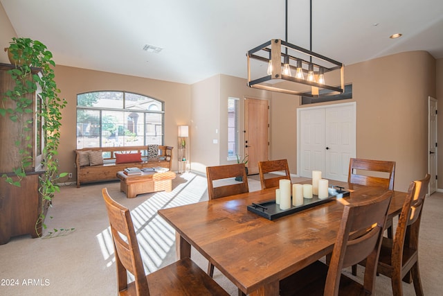 dining area with an inviting chandelier and light colored carpet