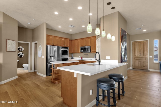 10254 N Demaret Dr, Fountain Hills, AZ 85268 - kitchen with a breakfast bar, sink, decorative light fixtures, light hardwood / wood-style flooring, and stainless steel appliances