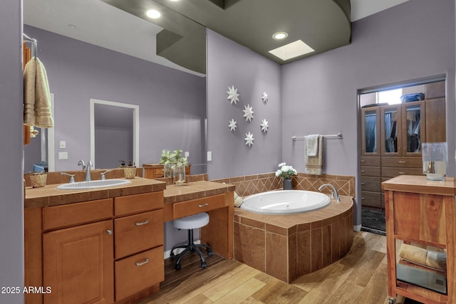 10254 N Demaret Dr, Fountain Hills, AZ 85268 - bathroom featuring vanity, hardwood / wood-style flooring, a skylight, and a relaxing tiled tub