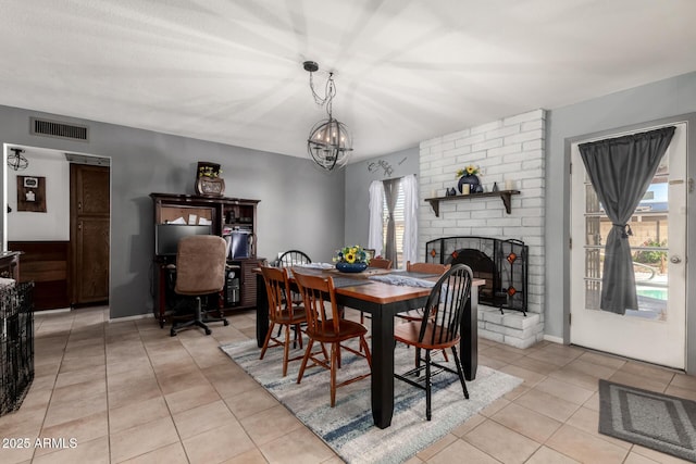 dining room featuring light tile patterned floors, visible vents, a notable chandelier, and a fireplace