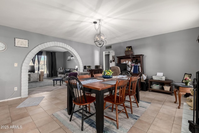 dining room with light tile patterned flooring, visible vents, arched walkways, and a chandelier