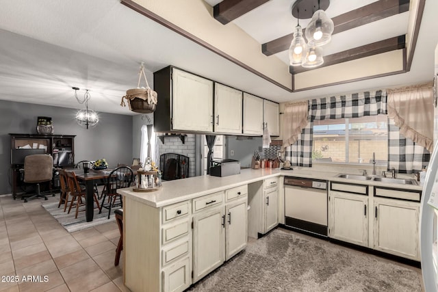 kitchen featuring a sink, a tray ceiling, a peninsula, white dishwasher, and light countertops