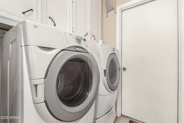 clothes washing area with washer and dryer, light tile patterned floors, and cabinet space