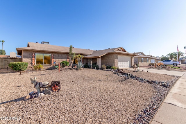 ranch-style house featuring brick siding, concrete driveway, a garage, and fence