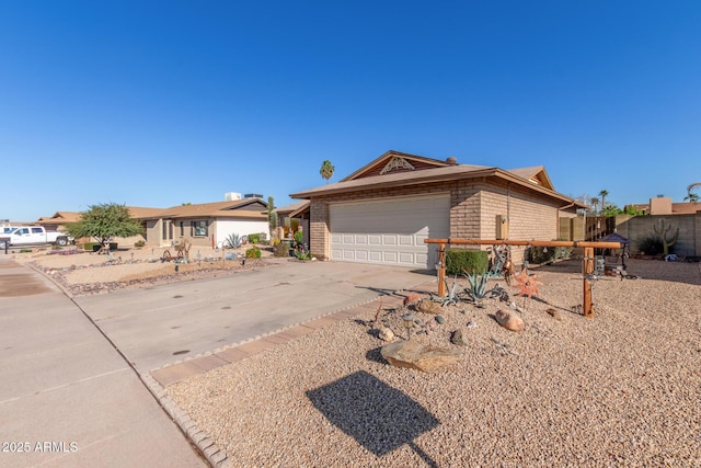 ranch-style home with a garage, brick siding, concrete driveway, and fence