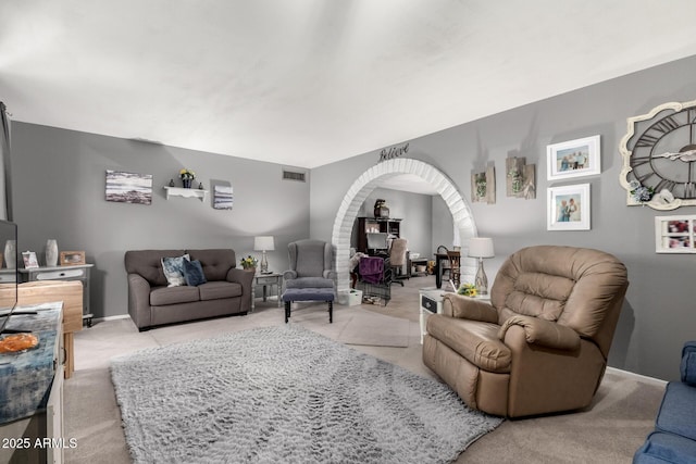 living room with visible vents, arched walkways, baseboards, and light carpet