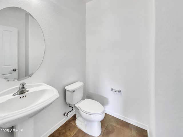 bathroom featuring tile patterned flooring, baseboards, a sink, and toilet