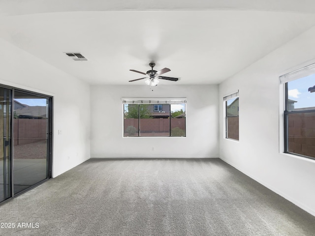 carpeted empty room featuring visible vents, baseboards, a ceiling fan, and plenty of natural light