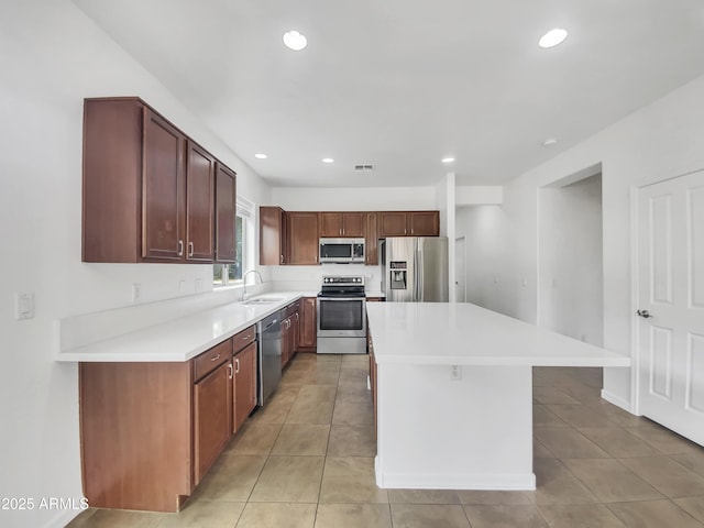 kitchen with light tile patterned floors, appliances with stainless steel finishes, a sink, and a kitchen island