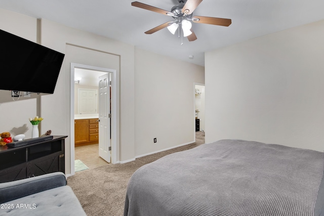 bedroom featuring light carpet, a ceiling fan, ensuite bathroom, and baseboards