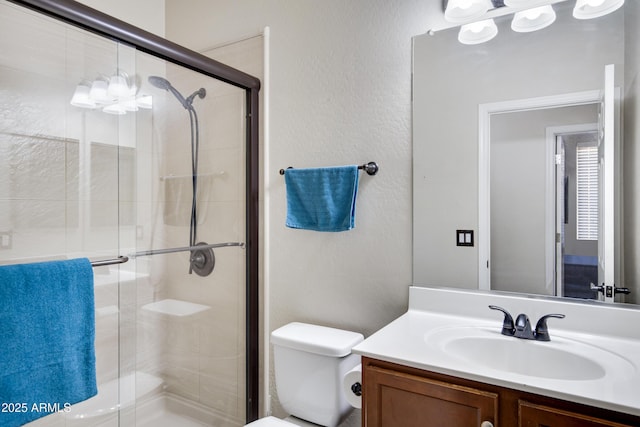 bathroom with vanity, a shower stall, and toilet