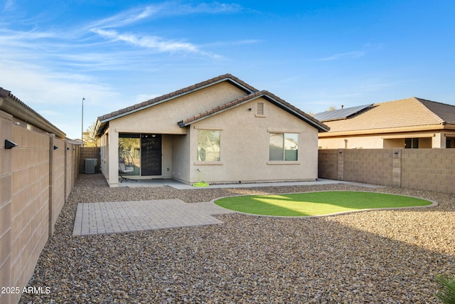 rear view of house with central air condition unit, a fenced backyard, stucco siding, and a patio area