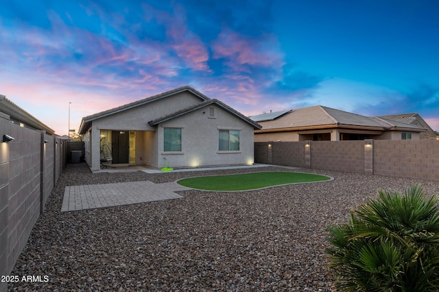 rear view of property featuring a patio area, stucco siding, a tile roof, and a fenced backyard