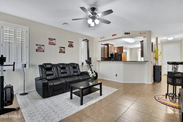 living room with light tile patterned floors, visible vents, baseboards, and ceiling fan