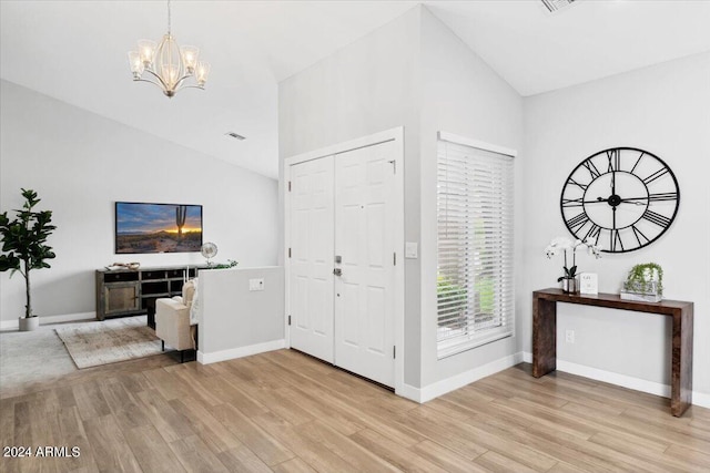 entrance foyer with an inviting chandelier, light wood-type flooring, and high vaulted ceiling