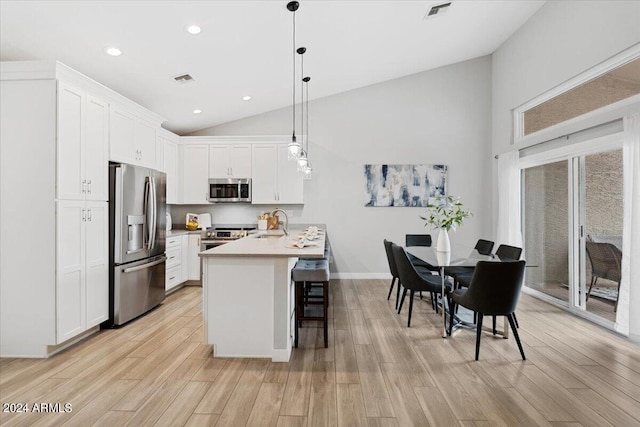 kitchen with white cabinets, appliances with stainless steel finishes, light hardwood / wood-style floors, and pendant lighting