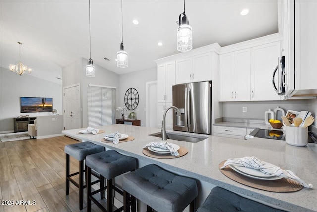 kitchen with pendant lighting, stainless steel appliances, light hardwood / wood-style flooring, white cabinetry, and lofted ceiling