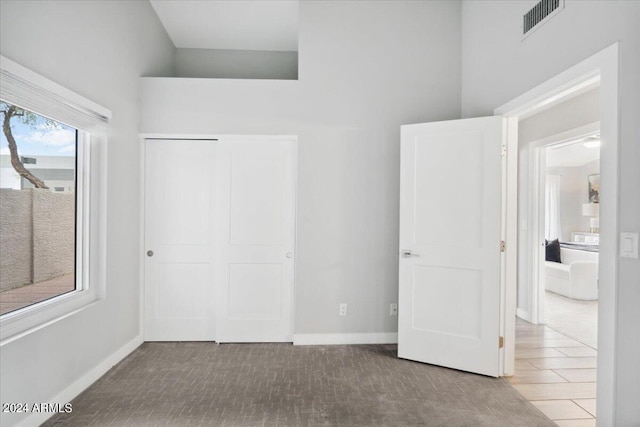 unfurnished bedroom with a closet, light carpet, and a towering ceiling