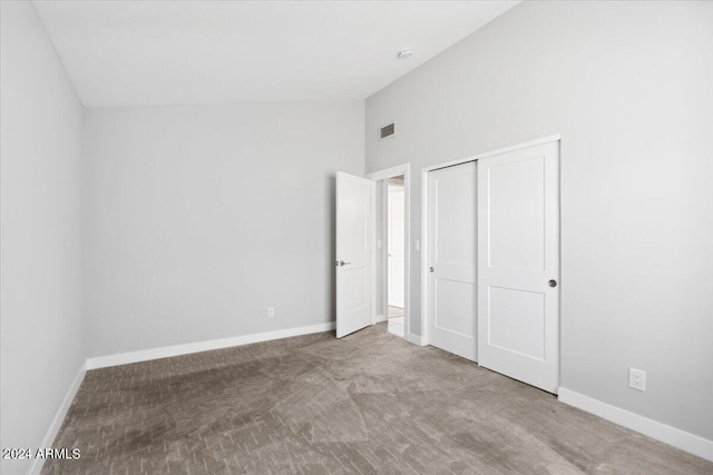 unfurnished bedroom with carpet flooring, a closet, and high vaulted ceiling