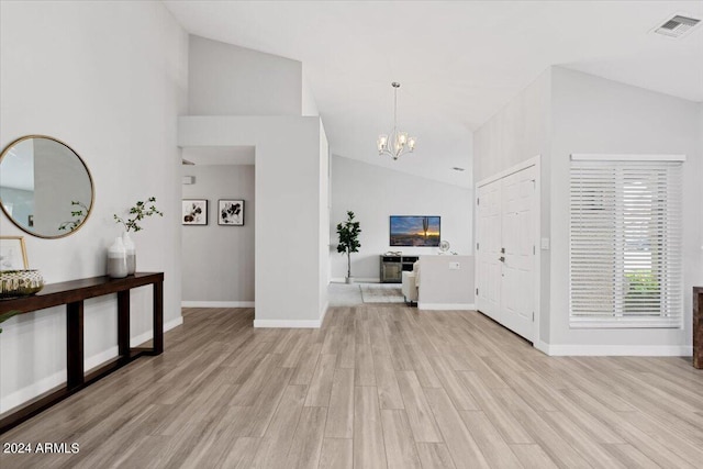 foyer entrance featuring light hardwood / wood-style floors, vaulted ceiling, and a notable chandelier