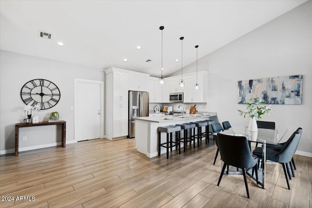 dining room with high vaulted ceiling and light wood-type flooring