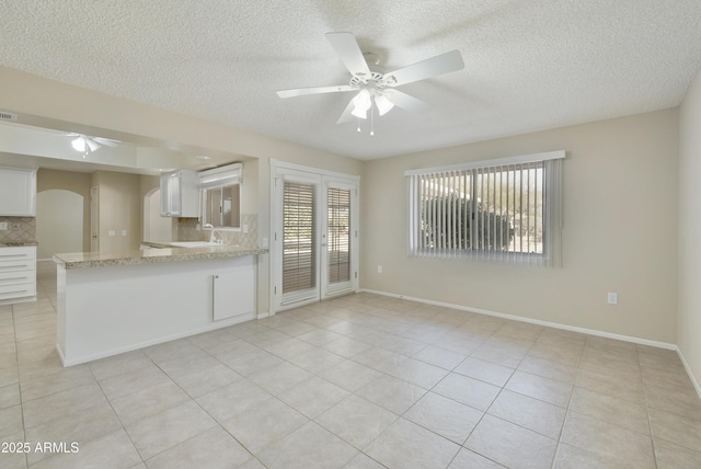 unfurnished living room featuring ceiling fan, light tile patterned floors, and a textured ceiling